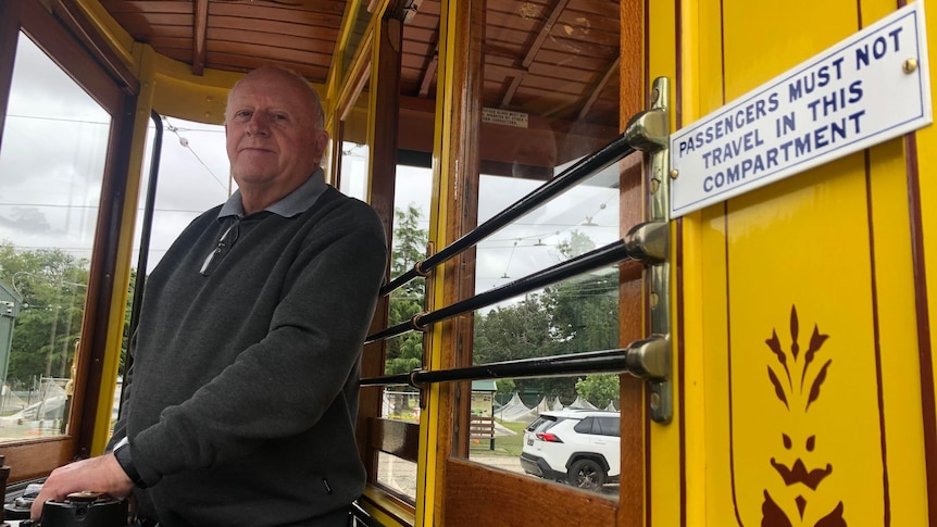 A man stands behind the wheel of a tram
