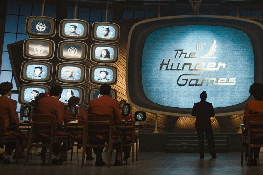 A wall of 1960s style screens, as characters watch a broadcast of The Hunger Games.