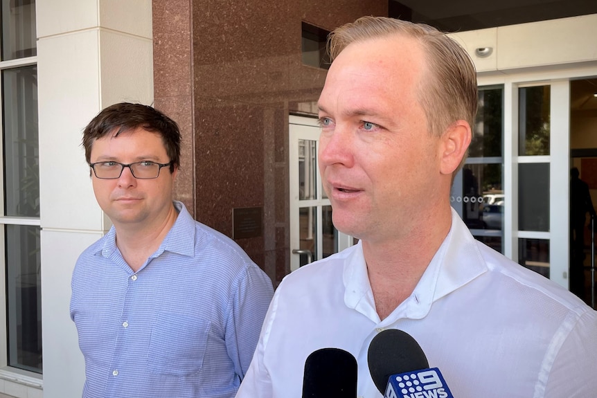 Two men standing outside the main entrance of the NT Supreme Court; the one closest to the camera is speaking.