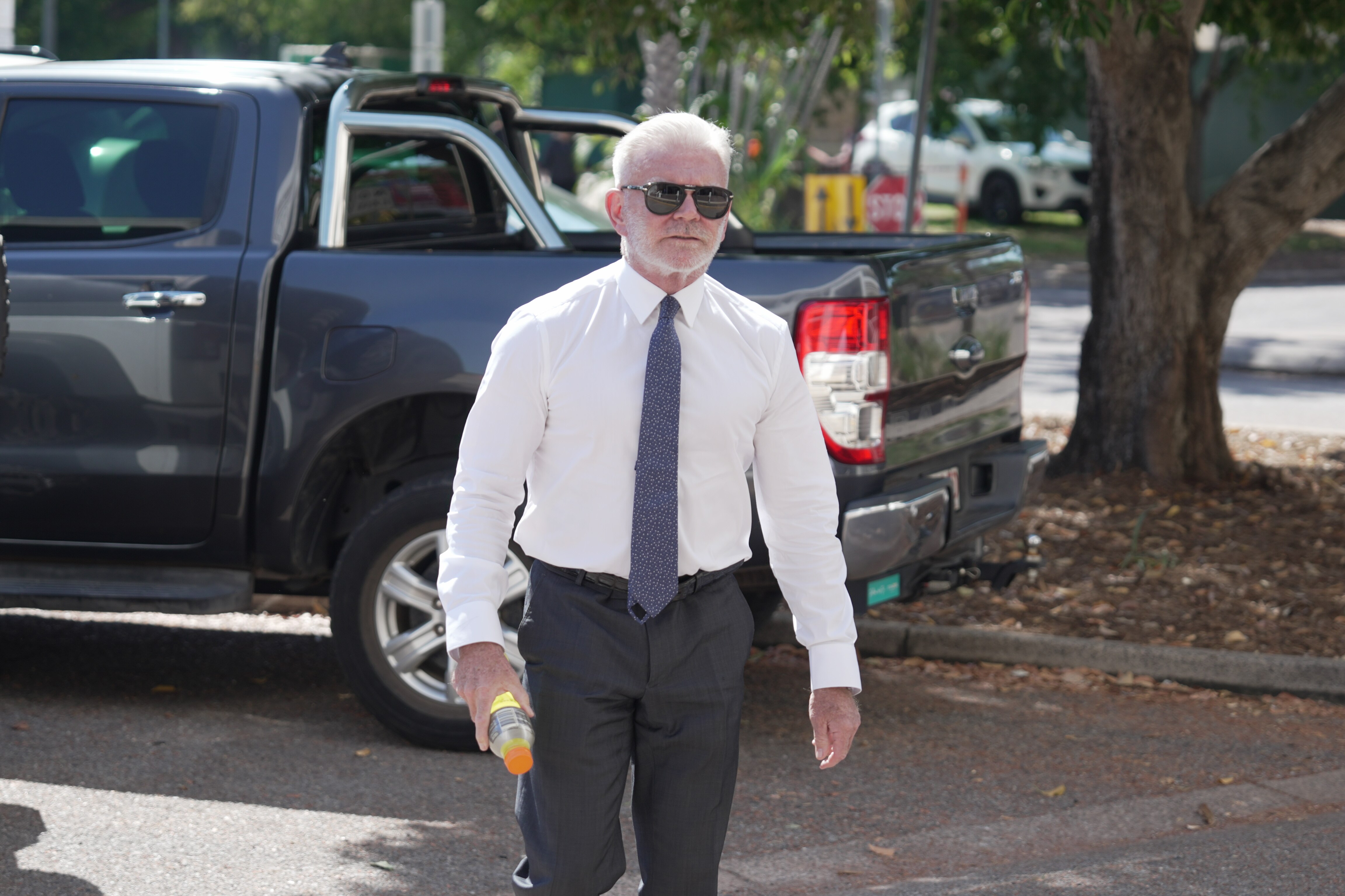 Lawyer walks through car park holding sports drink bottle
