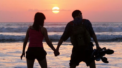 A couple watches the sun set at Kuta Beach on Bali.