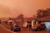 bushfire smoke can be seen rising behind houses in suburban Port Macquarie