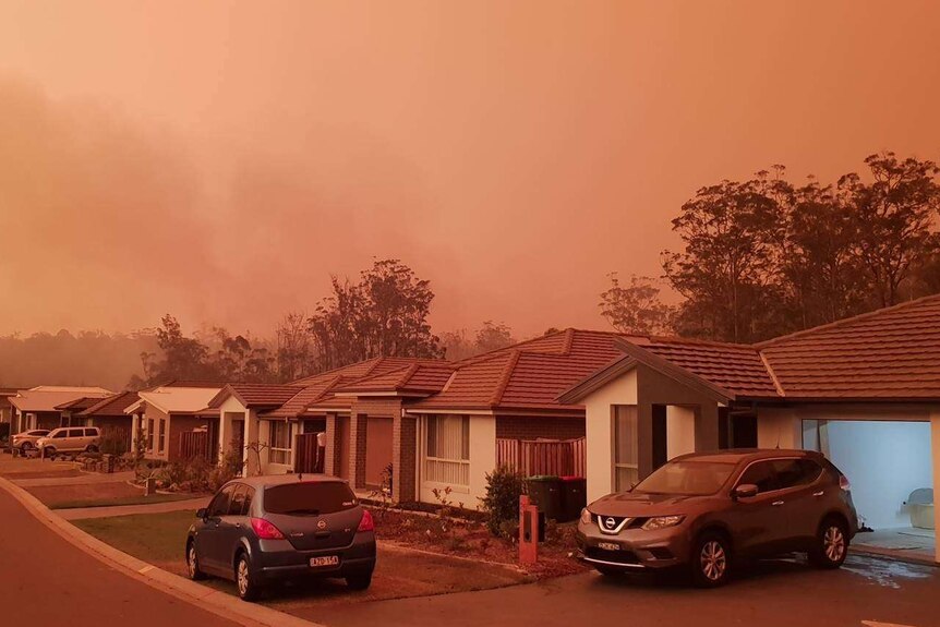 bushfire smoke can be seen rising behind houses in suburban Port Macquarie