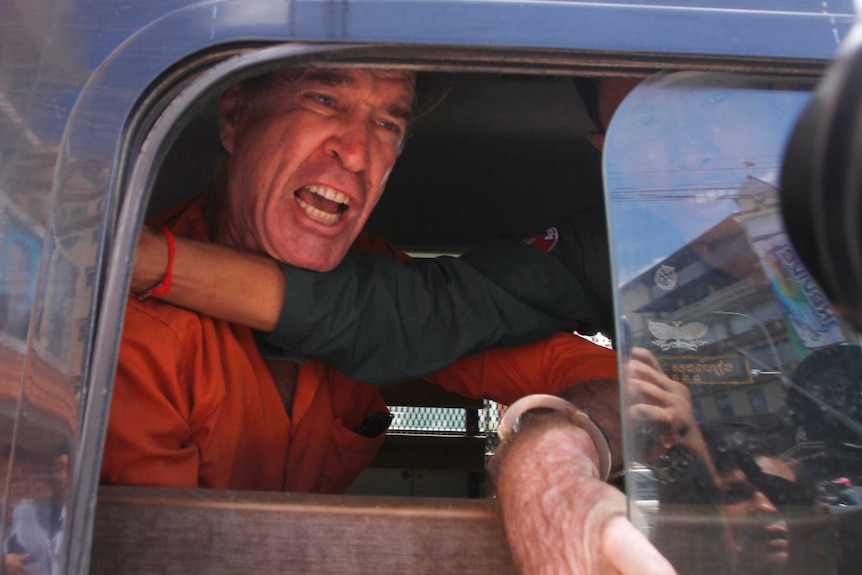 James Ricketson yelling from car window as an official holds in back with his arm