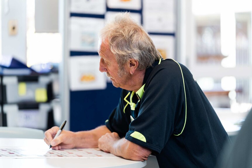 Older man sitting at desk writing