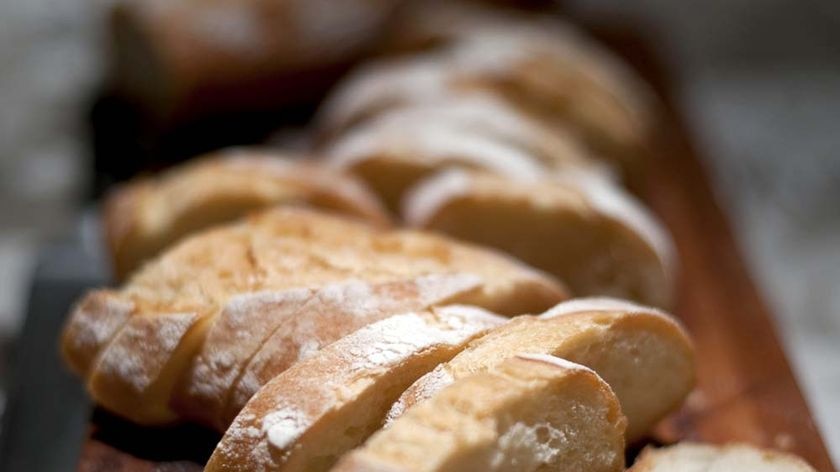 Thick slices of white bread sit on a wooden board.