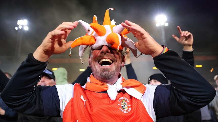 Luton Town fan with an orange and white hat on his face