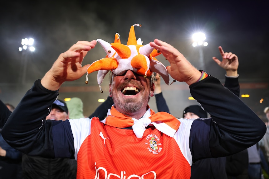 Luton Town fan with an orange and white hat on his face