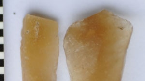 Two dark yellow-coloured stone-like objects, one in a triangular shape, the other more rectangular.