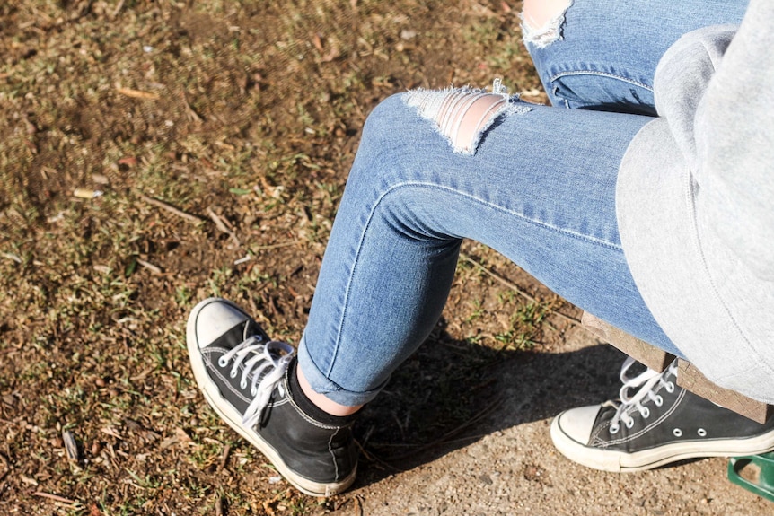 A girl in jeans and sneakers.