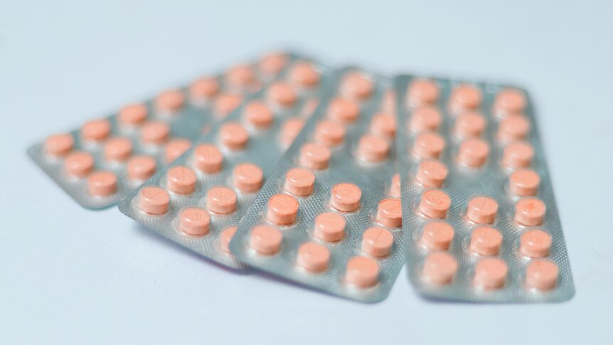 Generic orange contraceptive pills in the blister pack on blue backgrounds