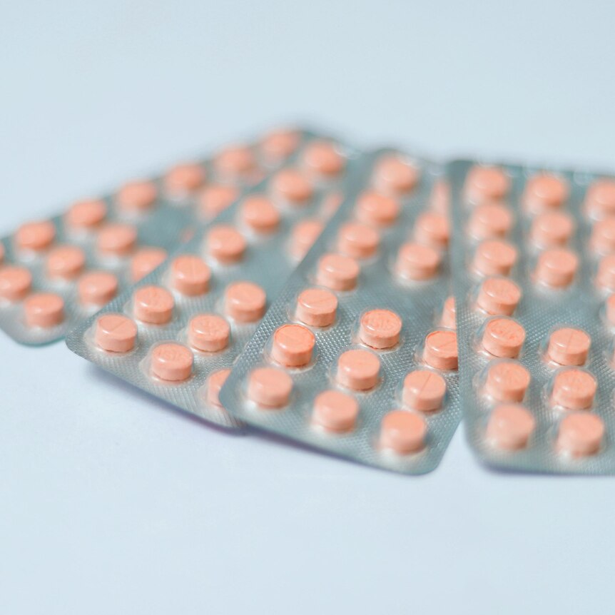 Generic orange contraceptive pills in the blister pack on blue backgrounds