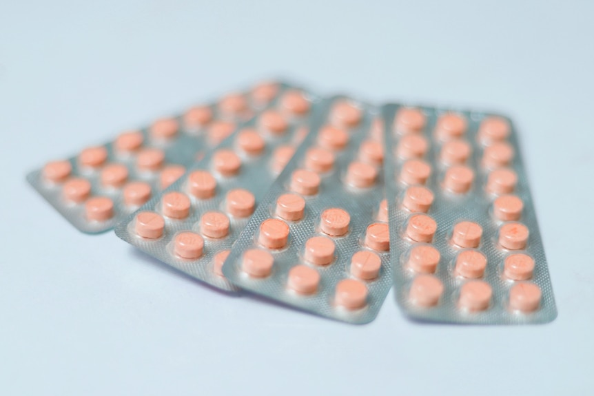 Generic orange contraceptive pills in the blister pack on blue backgrounds