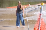a woman with blonde hair standing on a flooded causeway