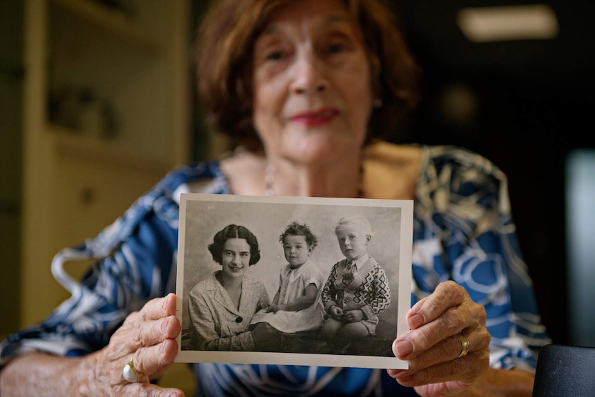 Wendy James holds an archival photo of her mother with herself and a sibling as children.