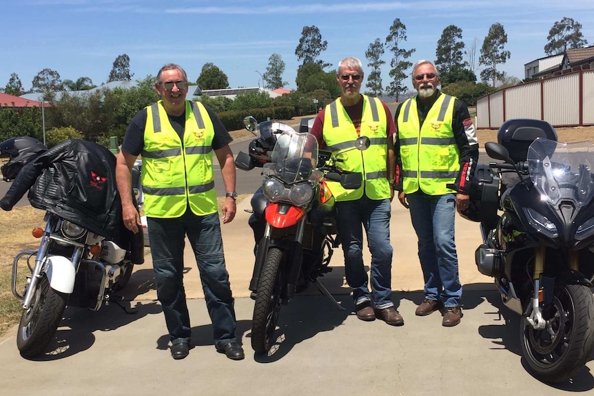 Three volunteers Blood Bikes volunteers stand beside their motorbikes.