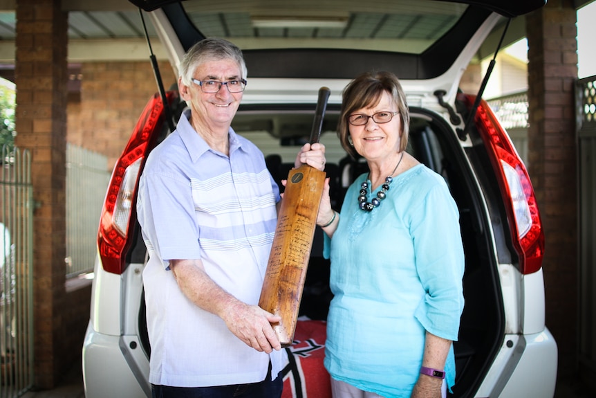 John Clancey and his wife Ann with the Bodyline cricket bat at the back of their car.