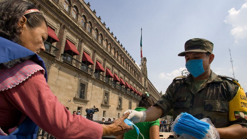 A soldier hands out masks outside the National Palace in Mexico City