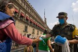 A soldier hands out masks outside the National Palace in Mexico City