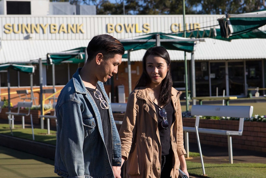 Mikey and Heidi Tai walking across Sunnybank Bowls Club greens.