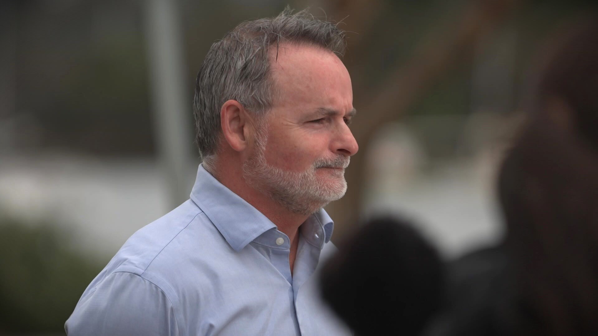 Side view of David O'Byrne at a press conference.