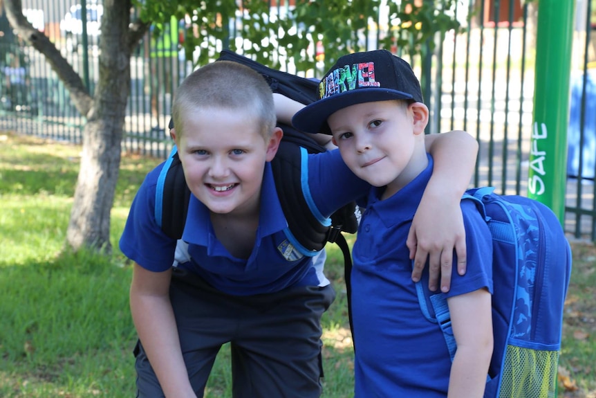 Two boys in school uniforms smiling and looking at the camera.