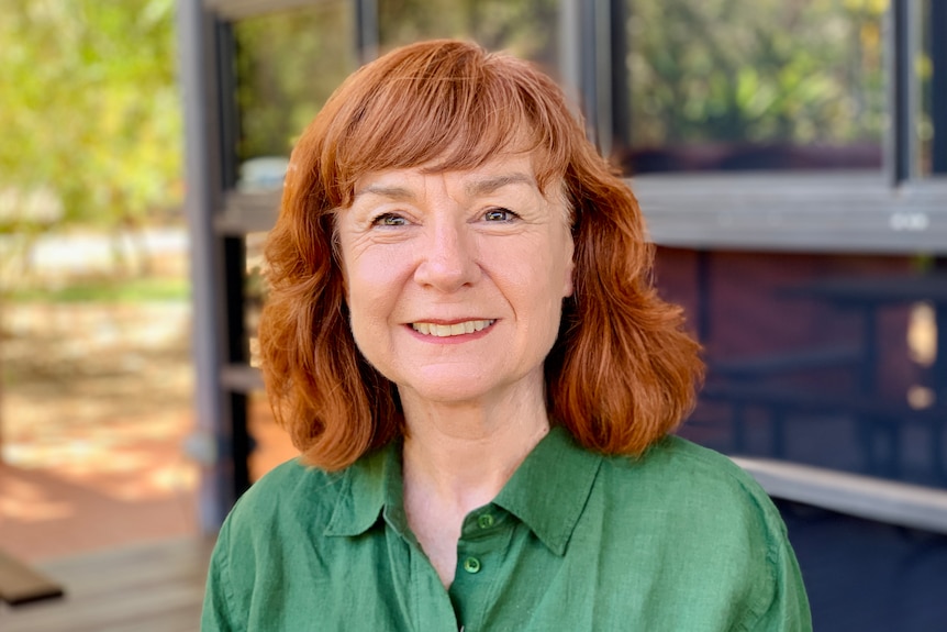 A woman wearing a green shirt smiles at the camera