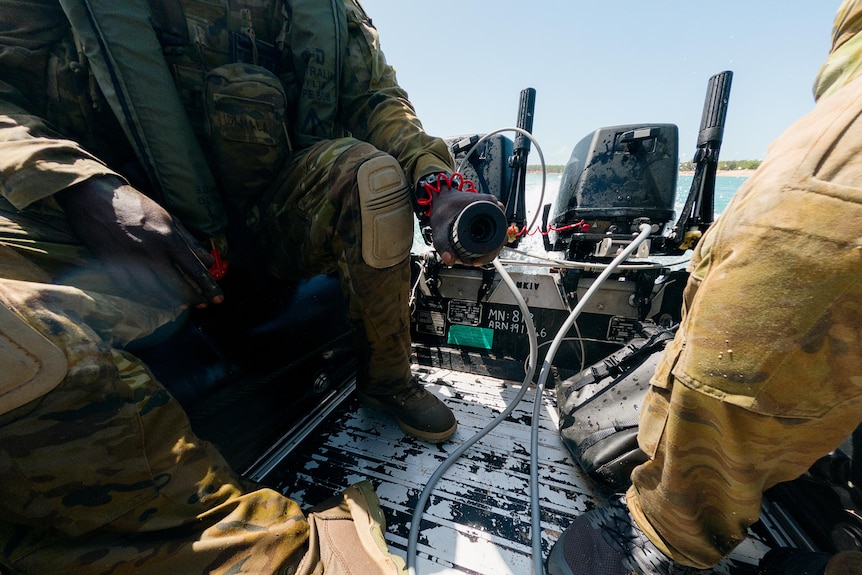 close-up of a man in army uniform driving an inflatable boat