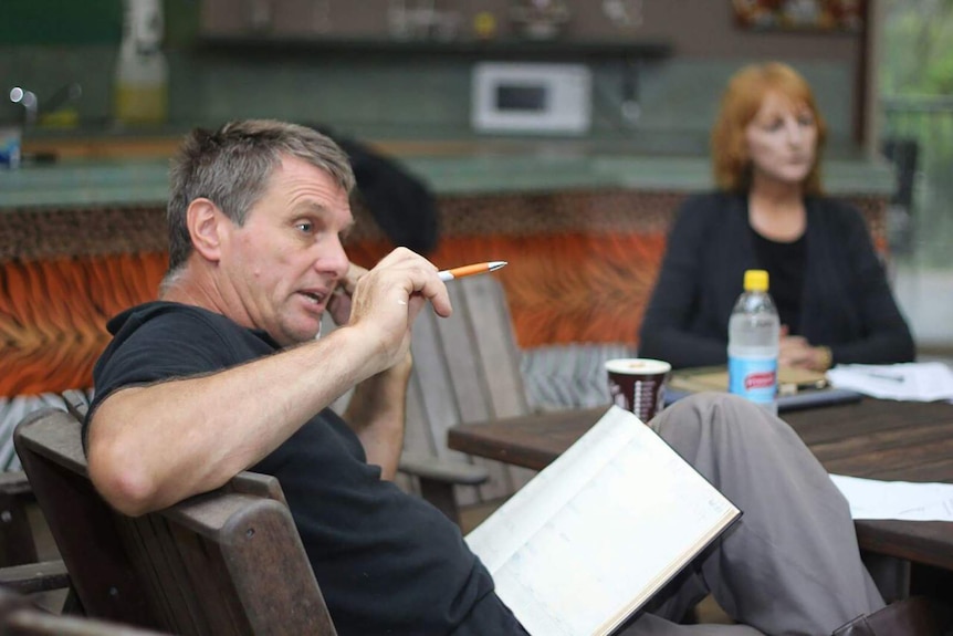 A photo of Tim Husband sitting at a table talking on the phone.