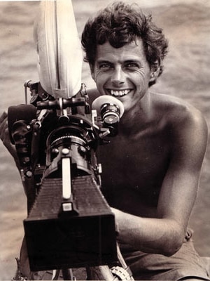 A black and white image of a young man behind a large video camera in the 1970s.