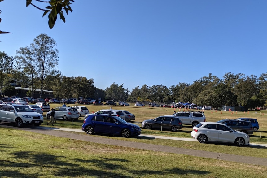 Long line of cars waiting to drive through pop-up COVID-19 clinic operating at Indooroopilly High School in Brisbane