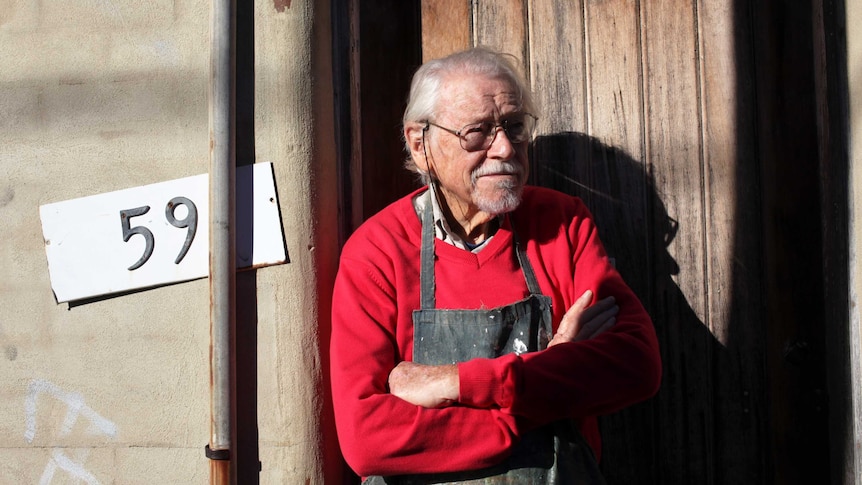 Guy Warren standing in front of his studio door