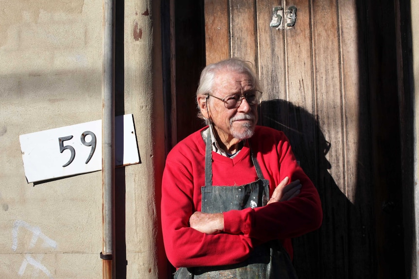 Guy Warren standing in front of his studio door