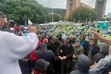 Police with clear shields in high-vis vests surround a crowd made up mainly of middle-aged men dressed in civilian garb 