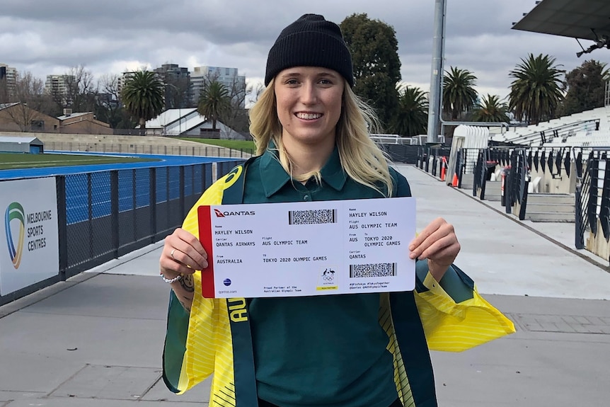 A girl stands smiling with a ticket