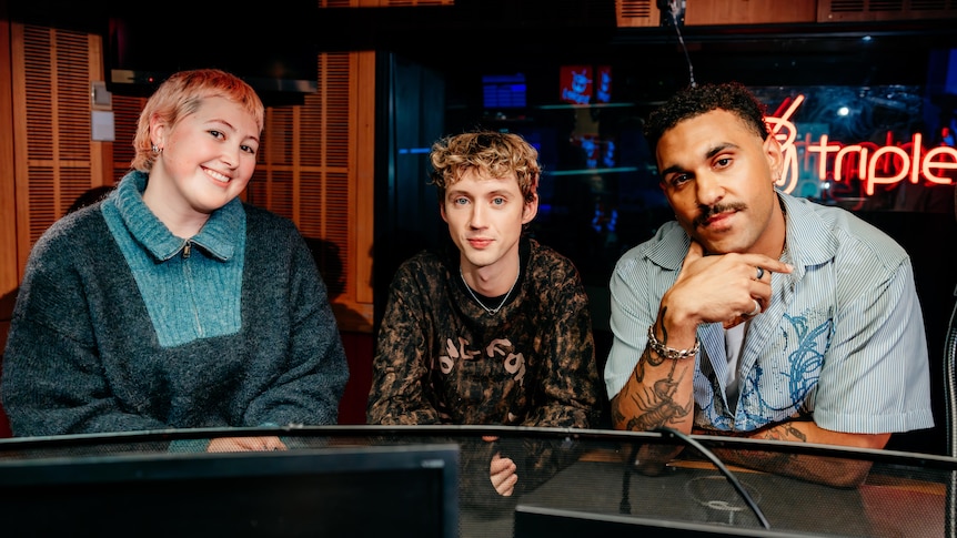 Abby Butler, Troye Sivan and Tyrone Pynor sit together behind the triple j presenter desk