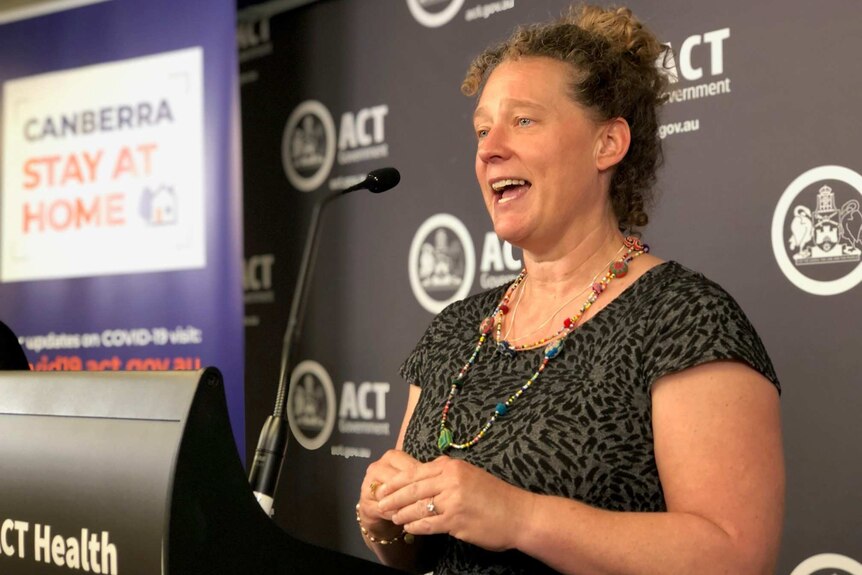 A woman stands behind a lectern.