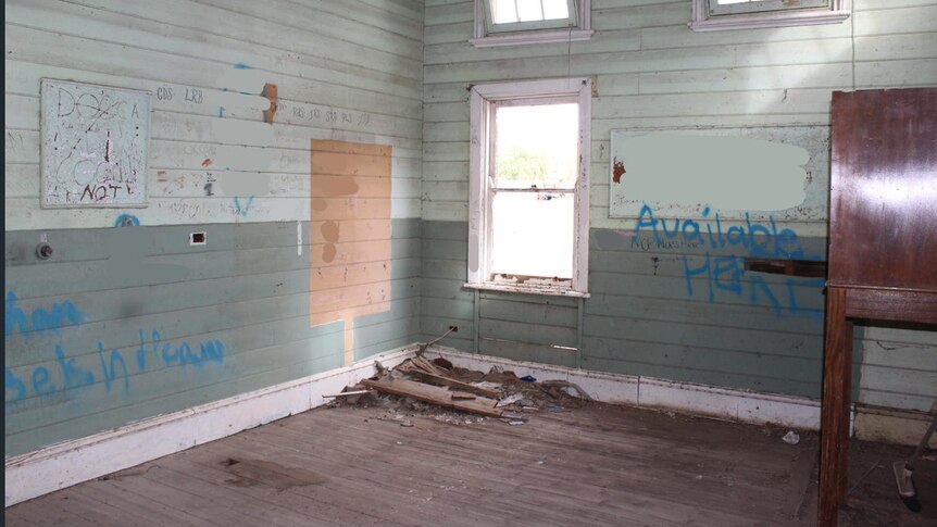A derelict interior empty room with blue graffiti scrawled across 
