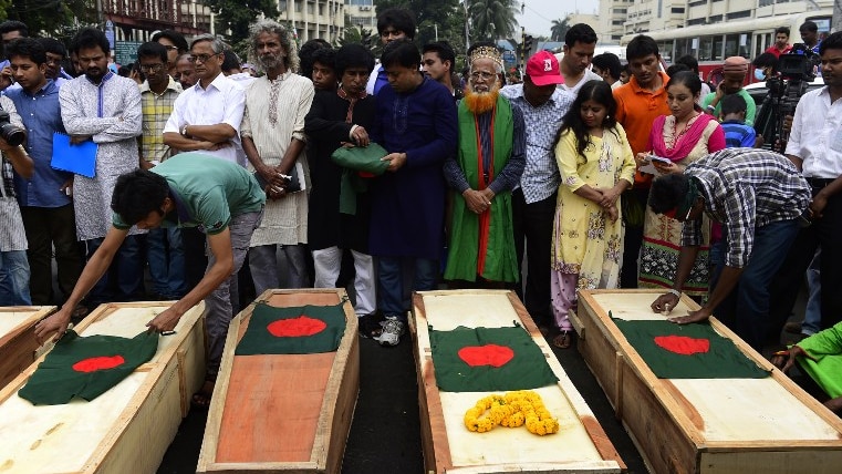 Bangladeshi activists place national flags on mock coffins, that symbolise the deaths of secular publishers and bloggers.