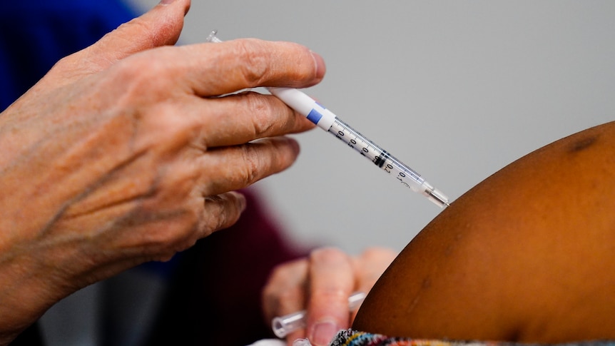 A health worker administers a dose of a COVID-19 vaccine