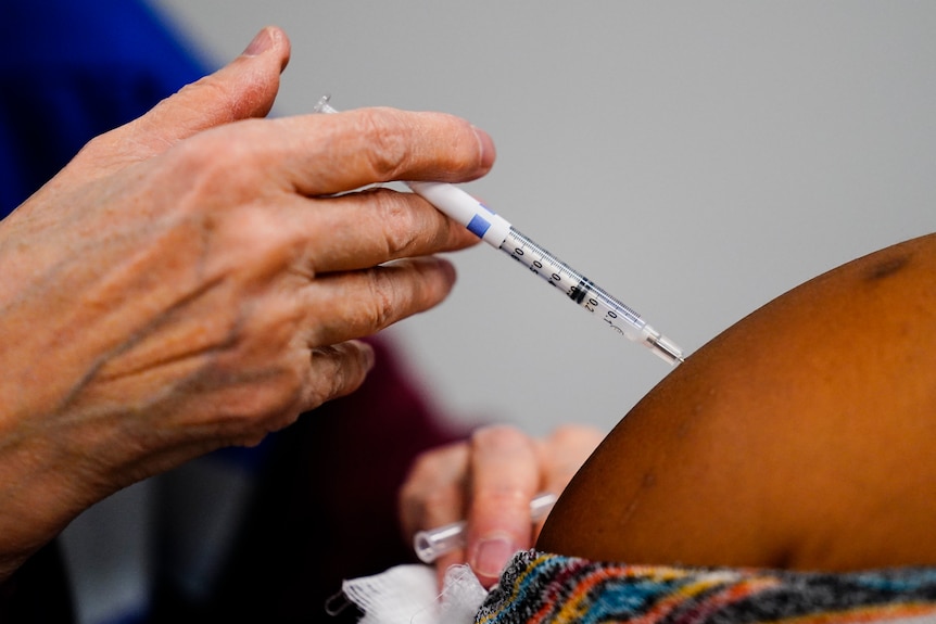 A health worker administers a dose of a COVID-19 vaccine