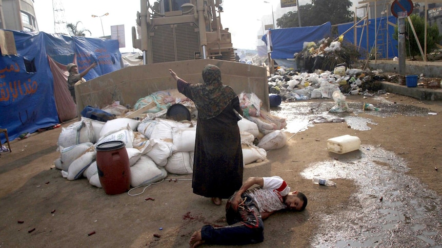An Egyptian woman tries to stop a military bulldozer from hurting a wounded youth.