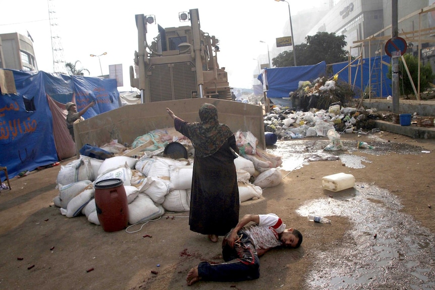 An Egyptian woman tries to stop a military bulldozer from hurting a wounded youth.