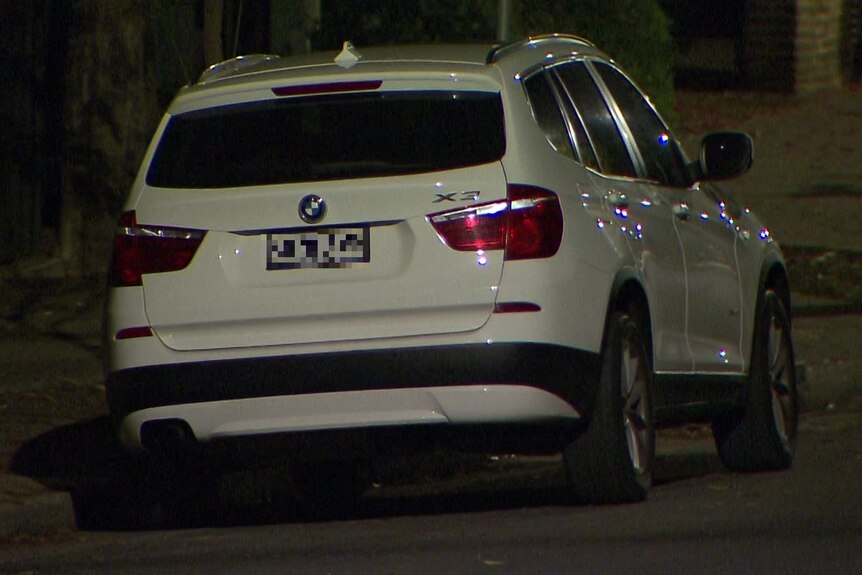 A white BMW SUV parked on a street at night