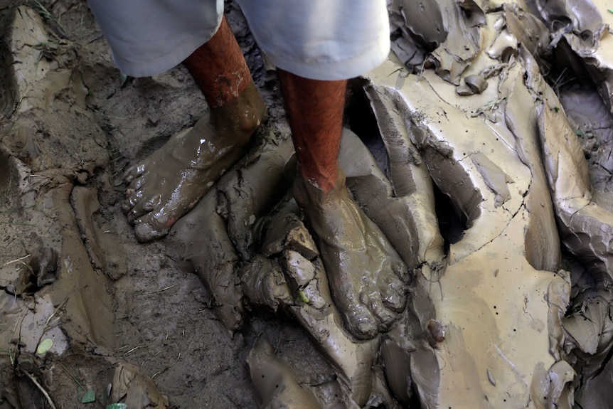 A person's feet covered in thick mud