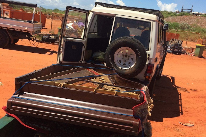 A photo of the piano found at the tip being towed away on a trailer.