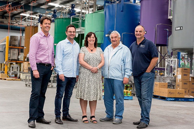 five people standing together looking at the camera in a warehouse