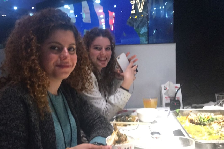 Aiia Maasarwe sits at a table with another young woman.