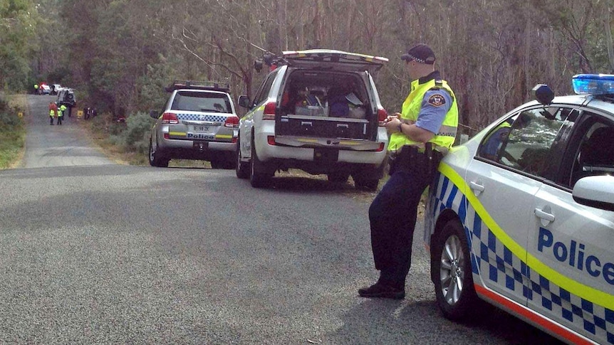 A police officer looks towards the site of a fatal crash involving a Targa Tasmania competitor.