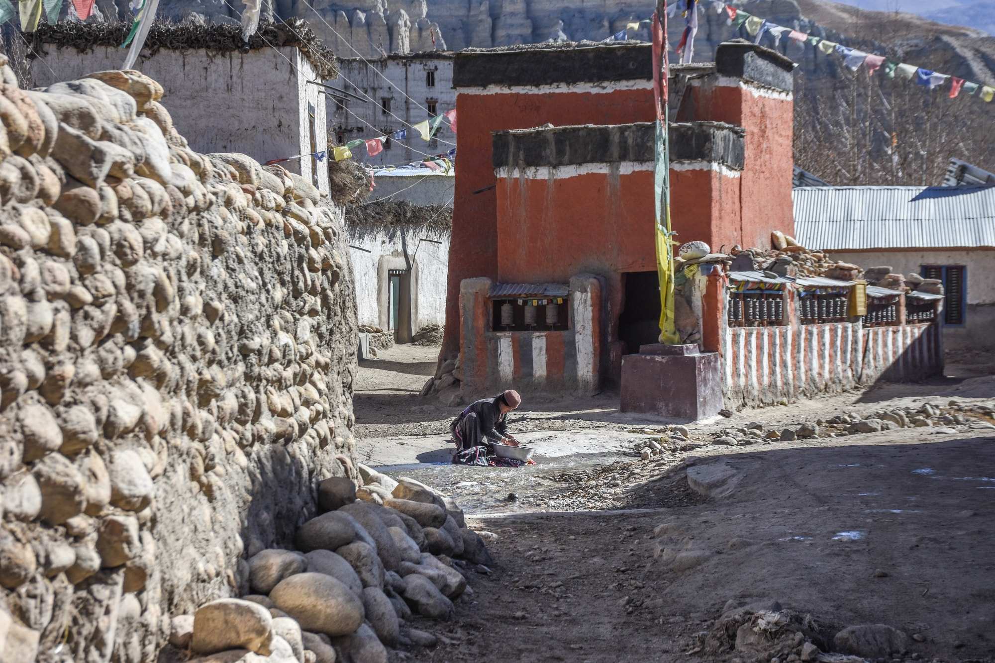 Woman cleans her clothes in a basin in the street